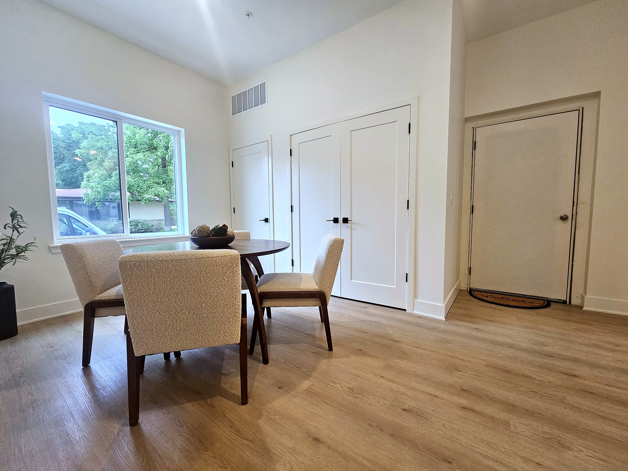 apartment dining room with circle wood trable with four white wool chairs